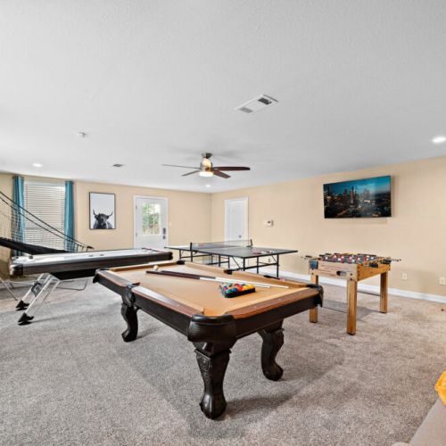 Game room with pool, air hockey, ping pong, and foosball tables, basketball arcade game, and dartboard.