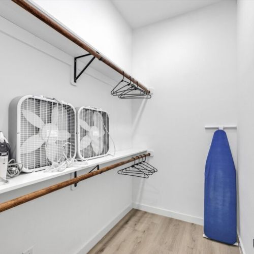Fully equipped walk-in primary closet featuring two portable fans.