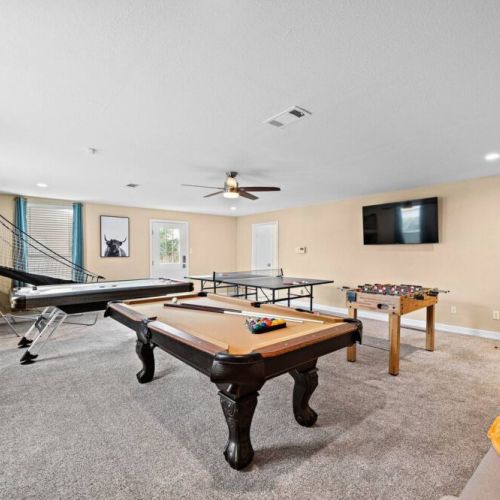 Game room with pool, air hockey, ping pong, and foosball tables, basketball arcade game, and dartboard.