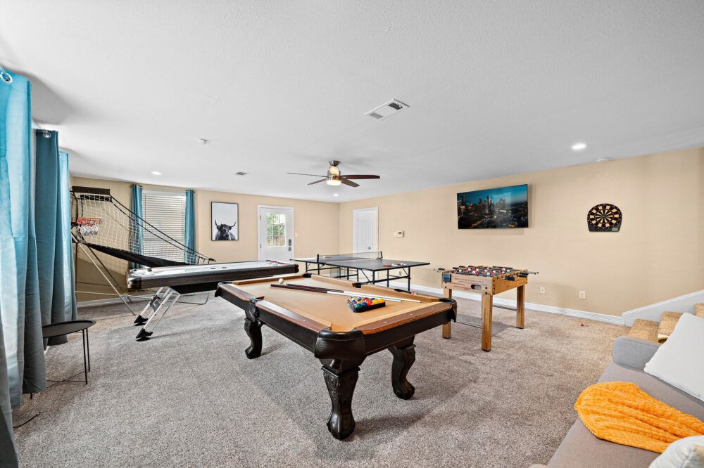 Game room with pool, air hockey, ping pong, and foosball tables, basketball arcade game, and dartboard.