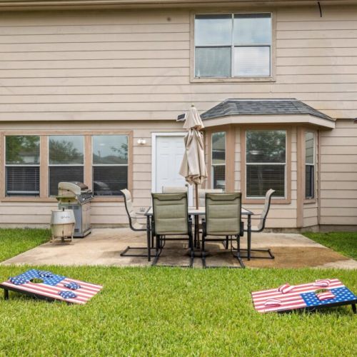 Backyard with gas and smokey grill, a cornhole set, and an additional dining area with 6 comfortable seats!