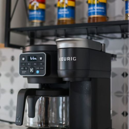 Keurig coffee machine with complementary coffee pods, tea, sugar, cream, and sweetener
