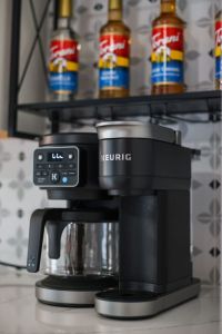 Keurig coffee machine with complementary coffee pods, tea, sugar, cream, and sweetener