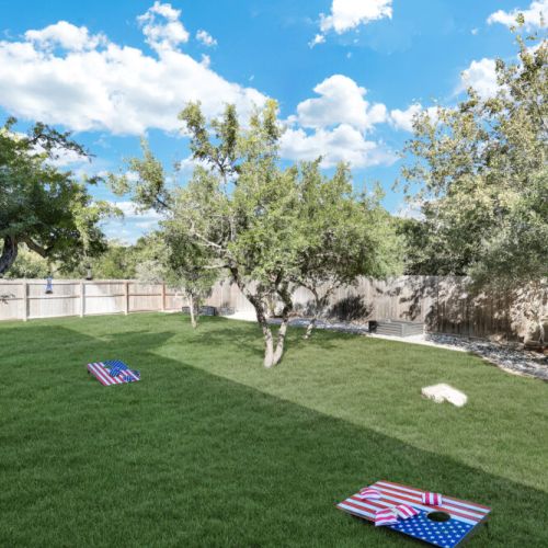 Spacious backyard with a cornhole set!
