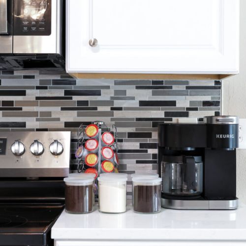Keurig coffee machine with complimentary coffee, coffee pods, decaf, tea, sugar, cream, and sweetener